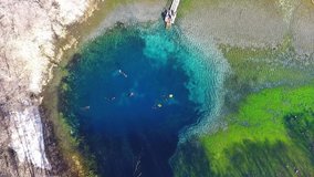 Top view of a clear cold blue lake. Divers in suits swim in clear, clear water. Water with blue minerals aerial view