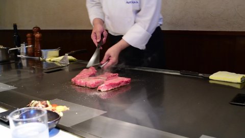 Kobe, Japan: October 11, 2018: A Japanese chef cooks Kobe beef steaks at a steakhouse. Kobe beef is a Wagyu beef raised according to strict standards in Japan.