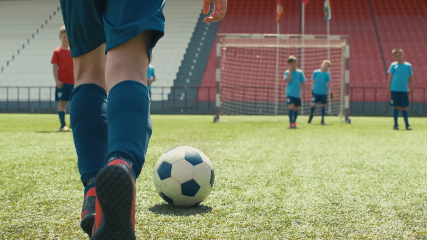 Tilt up shot of young soccer player dribbling ball through stadium, trying to shoot it, but miss the goal and hitting opposite player Royalty-Free Stock Footage #1033798865
