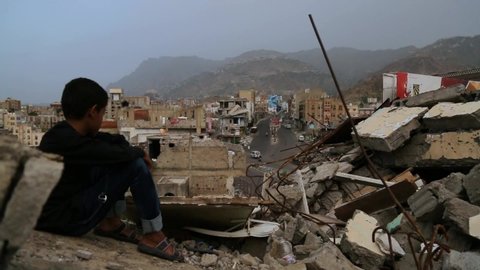 A child from Taiz City sits on the ruins of his ruined home because of the war on the city-Yemen.