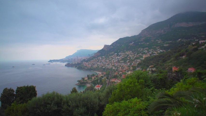 Monte Carlo, Monaco: City evening overlooking the city and the marina. Panoramic view of Monaco in the evening. Far plan. The city is far away. It is cloudy. Hotels and skyscrapers on timelapse
