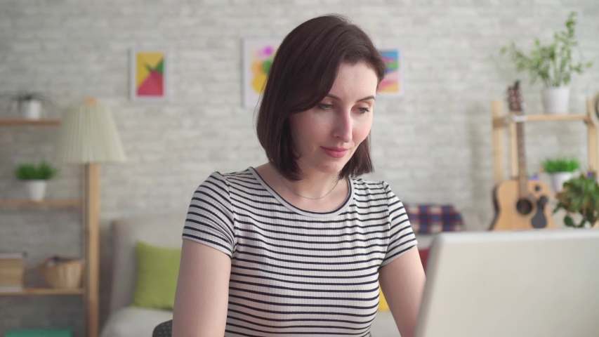 Young woman looking for information on the Internet in a laptop and holding a hearing aid close up