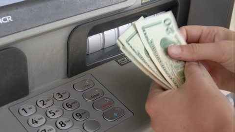 Los Angeles, CA / USA - July 14 2019: This close up video shows anonymous hands taking withdrawn money out of ATM machine and counting it.