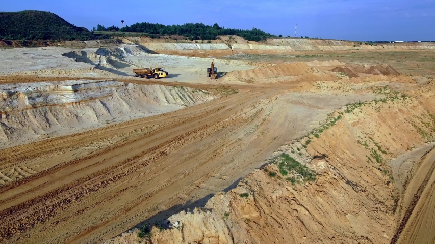 
drone overflight over a sand pit from a crane and an excavator away