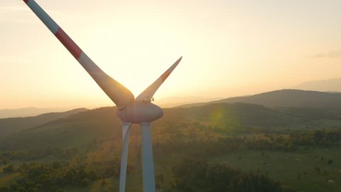 Aerial - Wind turbine blocking the sun with propeller at sunset