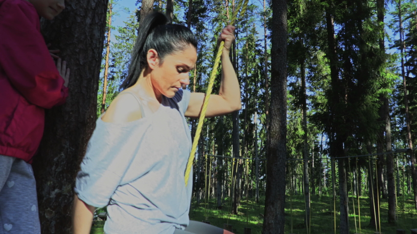 Woman hanging and rolling from cables between trees