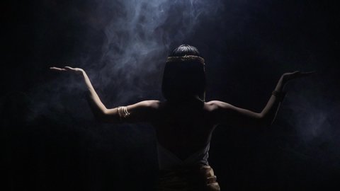 View from the back on Cleopatra standing in the smoke with her arms spread