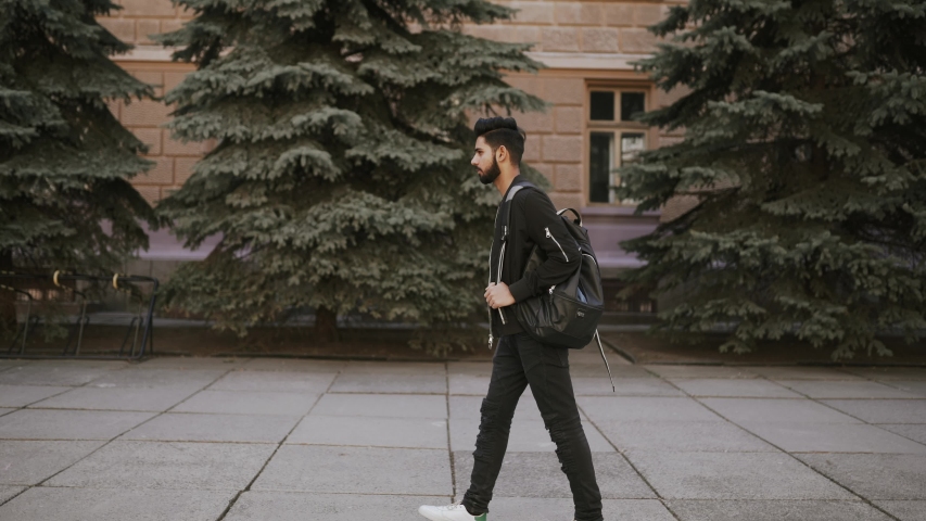 Young indian man with bag walking on the city street