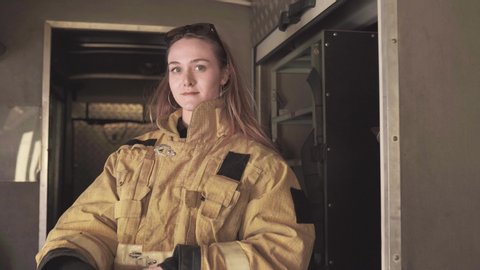 lady in firefighter uniform against firehouse equipment Arkivvideo