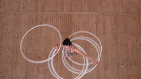 Art gymnastics. Dexterity woman rotate many hula hoop on scene. Top view.
