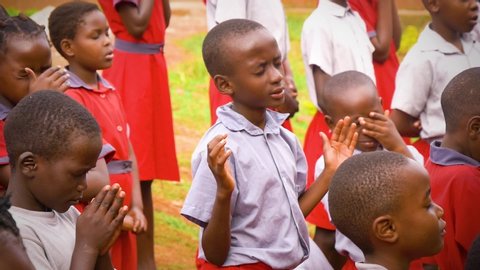 Namuwongo, Uganda - 11 07 2017: Medium shot of african children praying during assembly