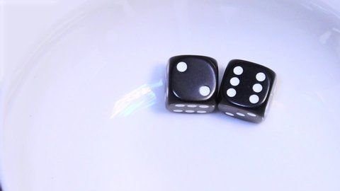Two black dice bounce and rebound in slow motion on a white background before resting at the numbers two and six, a total of eight.