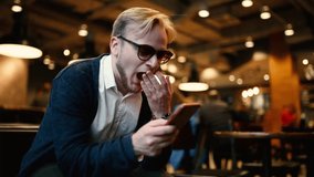 young male businessman hipster sitting in a cozy cafe restaurant and using a smartphone.