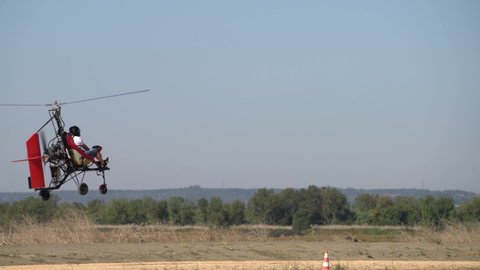 Ultralight gyrocopter autogyro with pilot flying low above the ground on high speed 