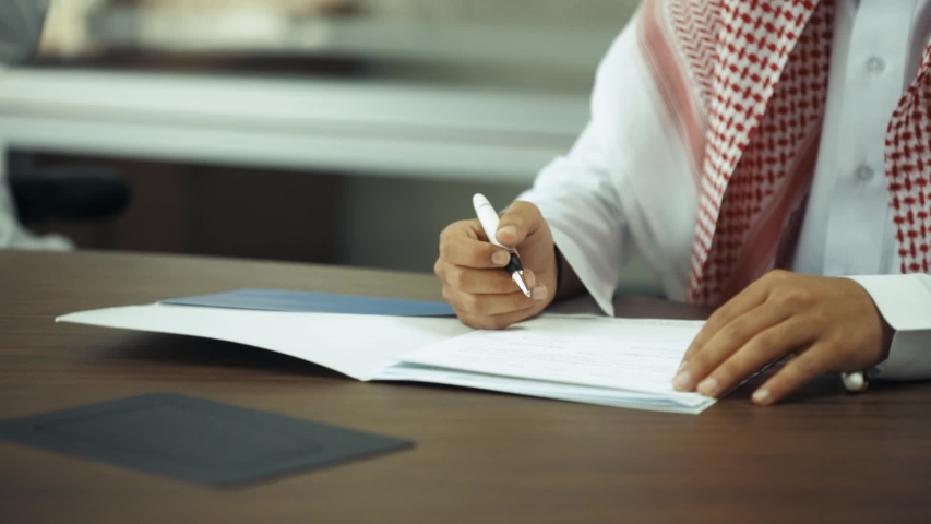 Saudi man signing contract in a business meeting | Shutterstock HD Video #1033875101