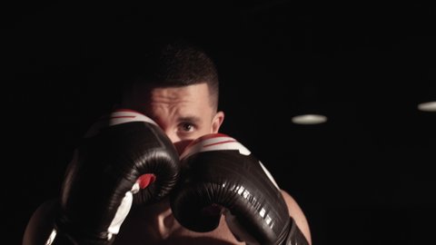 Close-up male boxer athlete boxing practicing punches in front of the camera