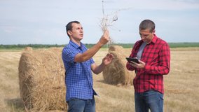 teamwork agriculture smart farming concept. two men farmers workers studying a haystack in field on digital tablet. teamwork slow motion video. people agronomist botanist farmers lifestyle working in