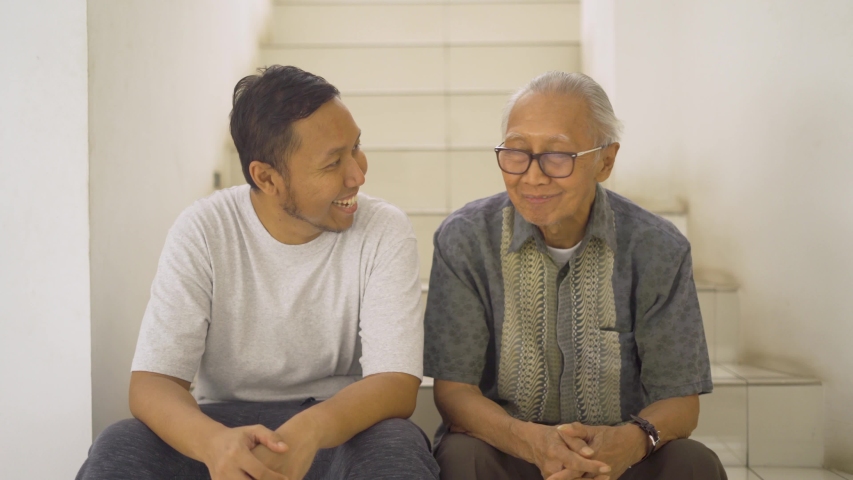Happy senior man talking with his son while sitting on the stair at home. Shot in 4k resolution | Shutterstock HD Video #1033896185