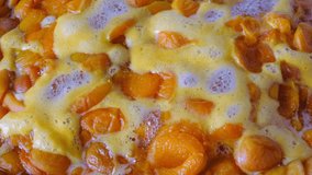 Cooking apricot jam from halves of pitted fruits in its own juice with sugar added close-up shot