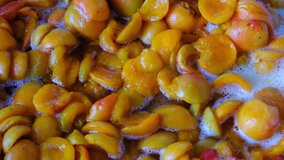 Cooking apricot jam from halves of pitted fruits in its own juice with sugar added close-up shot