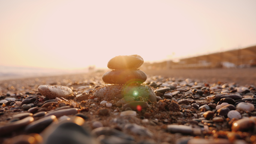 Hand puts stones in the pyramid, the sun