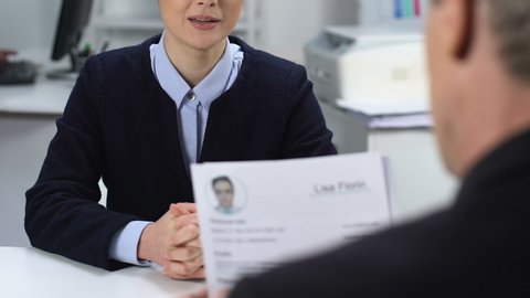 Female job candidate feeling nervous during interview, male manager reading cv