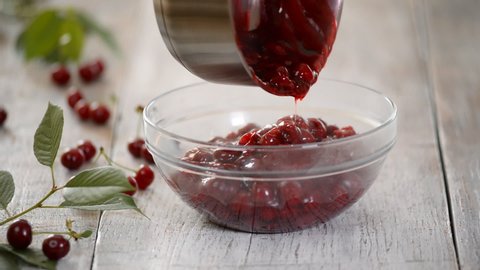 Pouring cherry filling into a glass bowl. Woman making cherry pie on the kitchen