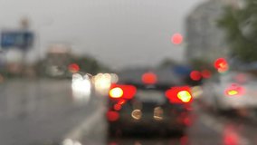 glare on the windshield of the car in the rain from drops, stop lights and oncoming headlights in traffic with the effect of blur and bokeh