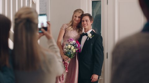 teenage couple prom night teens posing for photo with proud mom photographing teenagers for homecoming dance wearing stylish fashion excited for glamorous event 4k