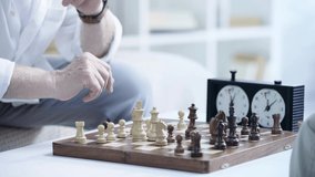 cropped view of senior man playing chess and pressing button on chess clock