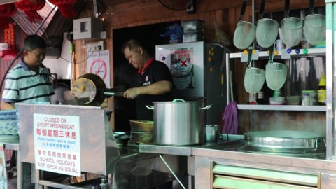 Penang / Malaysia - July 25th 2019: A cook is preparing food for his customer at the food stall.