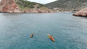 Aerial view of kayaker paddling forwards, authentic video. active summer sports, kayakers training. Two kayaks in sea drone shot.