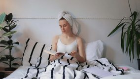 young caucasian girl with towel on head reading book and studying early dawn morning