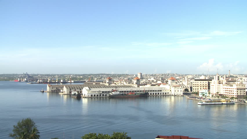 Wide shot of the port / docks area of Havana, Cuba. Warehouses and a cargo ship is visible in the distance.