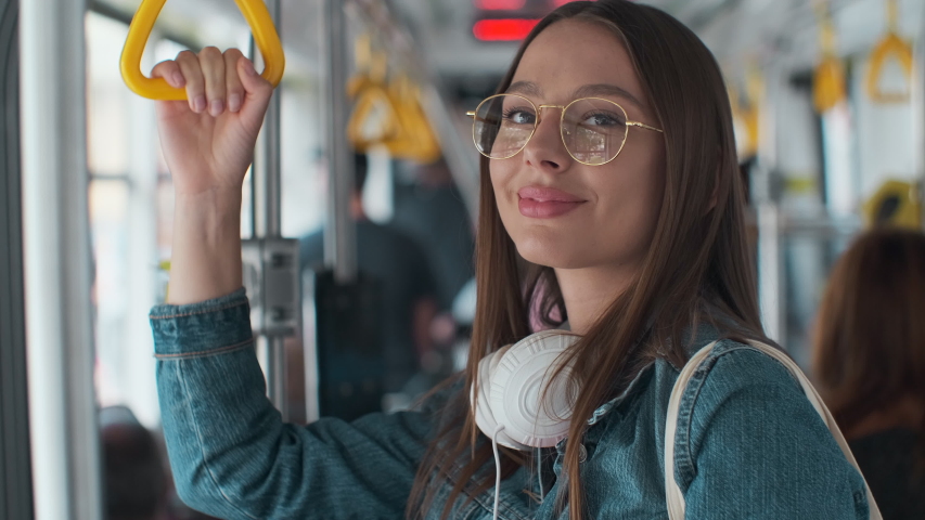 Young stylish woman enjoying trip in the modern tram, standing with coffee in the public transport