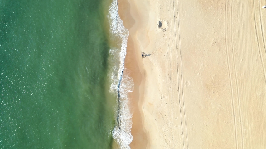 Bicyclist riding along golden beach (Virginia Beach). Distant aerial view.