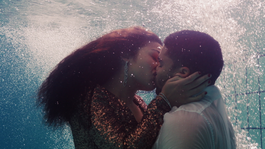 romantic couple kissing underwater in swimming pool wearing clothes young people in love enjoying intimate kiss lovers submerged in water floating with bubbles in passionate intimacy