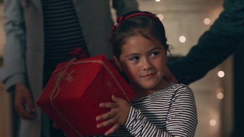 happy little girl excited to open present on christmas shaking gift box curious child enjoying festive holiday celebration with family at home 4k