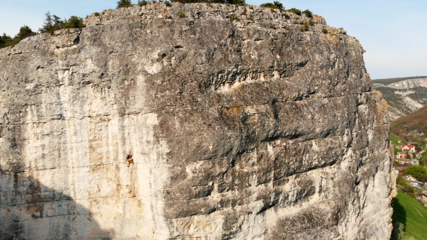 Aerial view of strong woman rock climbing, extreme vertical wall climb. Rock climbing dangerous mountain, active sport summer activity. Female climber, climbing gear, drone view