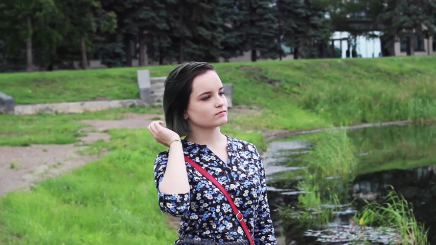 The girl stands on the shore of the lake and looks around.