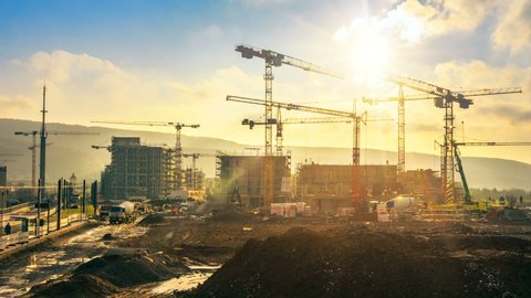 Time-lapse footage of a large construction site with several busy cranes in golden sunlight