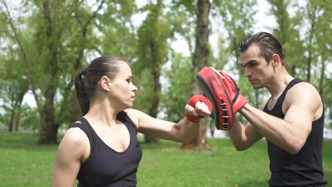 Slow motion.Training boxing process of woman  and man in city park area outdoor. Steady shot