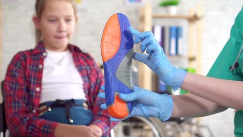 Orthopedic doctor tells a teenage girl about orthopedic insoles close up slow mo