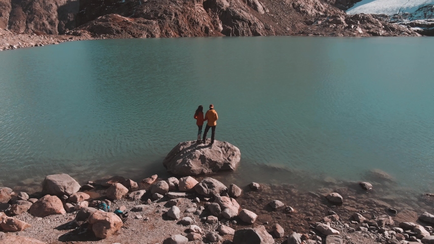 Aerial panoramic footage of young couple hiking the Mount Fitz Roy trek, showcasing the beautiful Patagonia, Argentina, mountain landscape