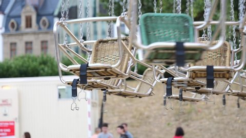 Düsseldorf, Germany - JULY 2019: Close up view of slow moving empty seat without people of swing ride or swing carousel with blur background of amusement park at Rheinkirmes Carnival.