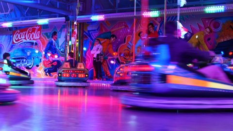 Düsseldorf, Germany - JULY 2019: Low angle view of people ride bumper cars, hit and bump, and atmosphere of disco light and amusement park at Rheinkirmes, annual amusement park in summer season.
