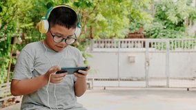 Asian kid boy are practicing skill playing online games on smartphones. E-sport competition is considered sports game in modern times that can earn money from children. And should wear optical filters