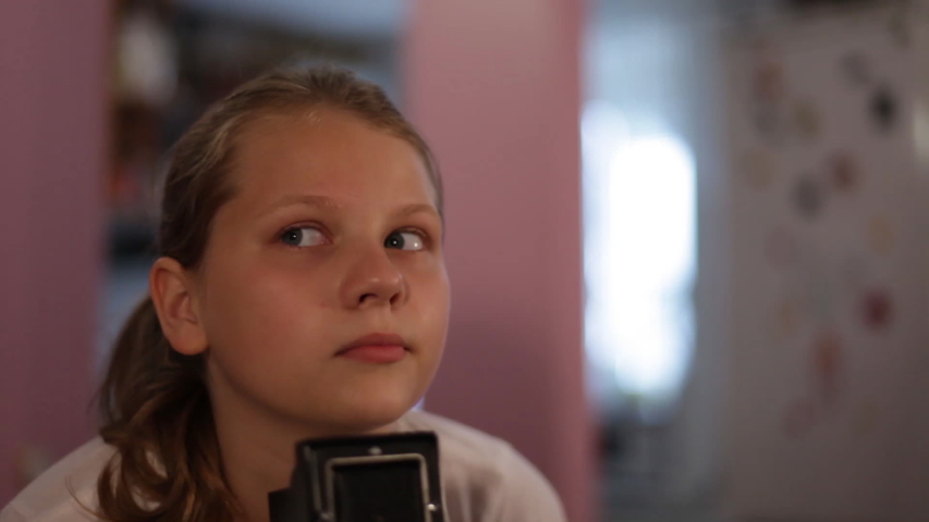 teen girl looks into the mine of a medium format camera aimed at us, taking picture of you.
