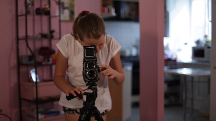teen girl looks into the mine of a medium format camera aimed at us, taking picture of you.