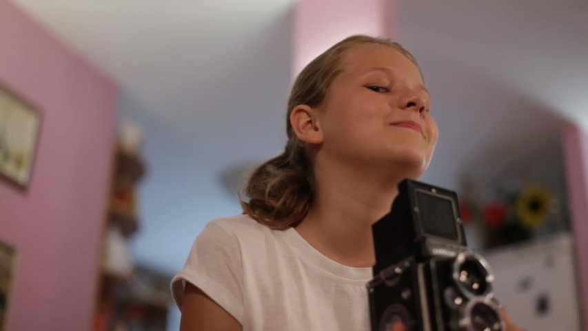 teen girl looks into the mine of a medium format camera aimed at us, taking picture of you.
